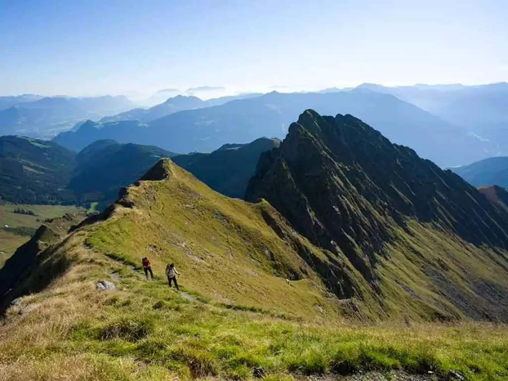 Wanderer gehen am Berggrad endlang mit toller Aussicht auf Umgebung